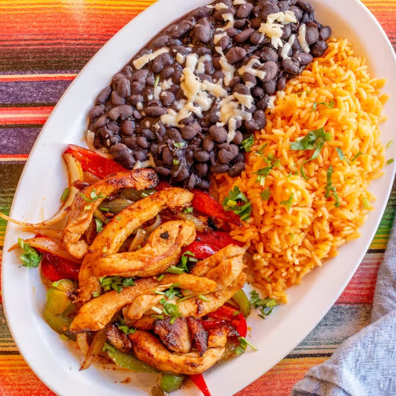 Chicken fajitas with grilled peppers and onions, served with rice and cheesy black beans.