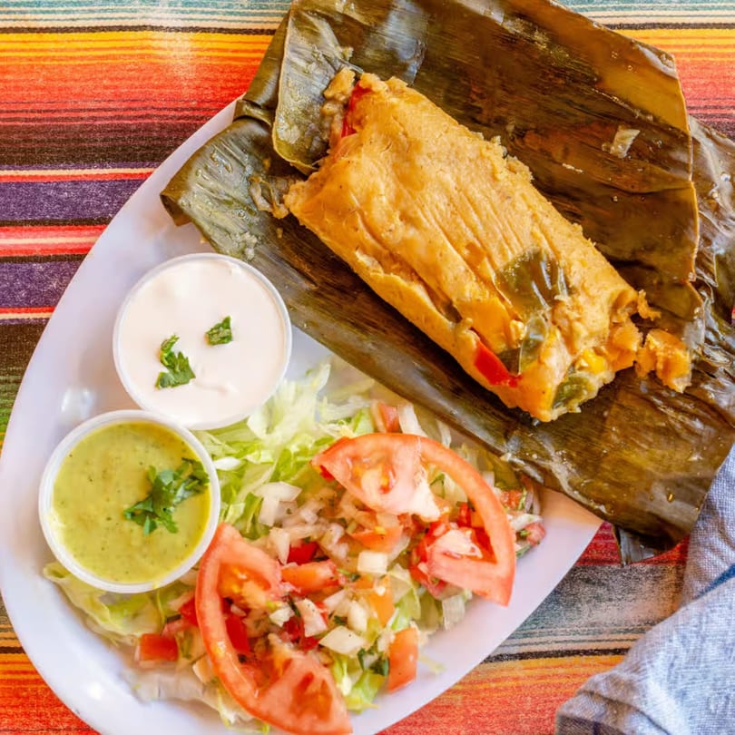El Vaquero Mexican Taqueria's tamale, unwrapped from a banana leaf, served with salad and two sauces.