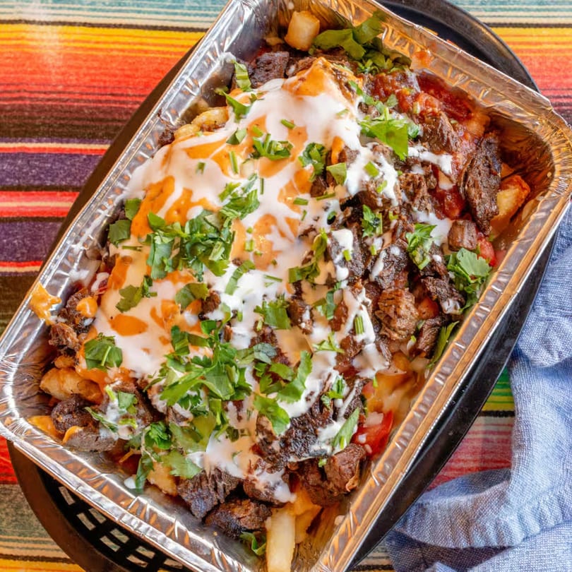 El Vaquero's carne asada fries, topped with sour cream, cheese sauce, salsa, and cilantro.